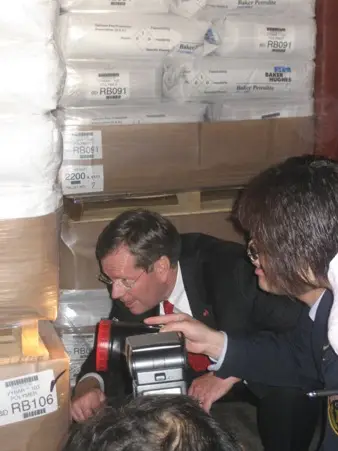 The Honorable Michael O. Leavitt, U.S. Secretary of Health and Human Services, joins officials from the Shanghai Entry-Exit Inspection and Quarantine Bureau to look at goods in a container at the Waigaoqiao Section of the Port of Shanghai.